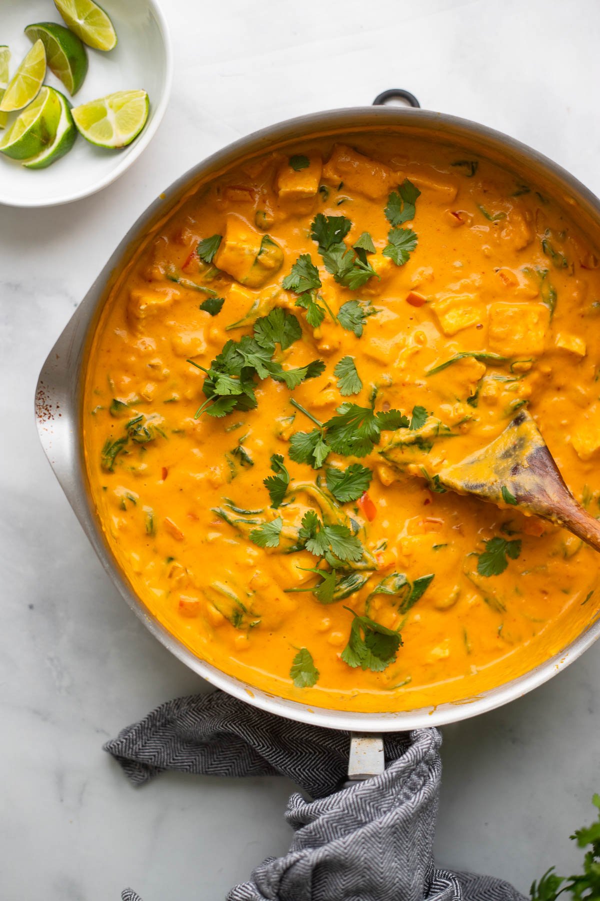 tofu pumpkin curry in large skillet with spoon garnished with cilantro.