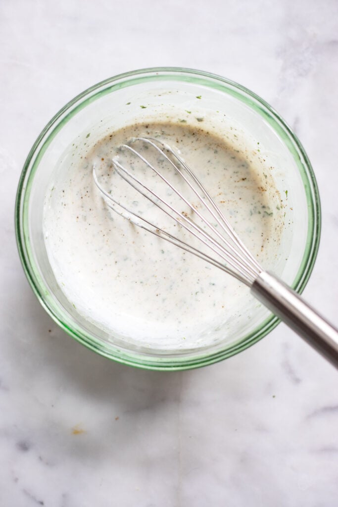vegan ranch dressing in bowl with whisk.