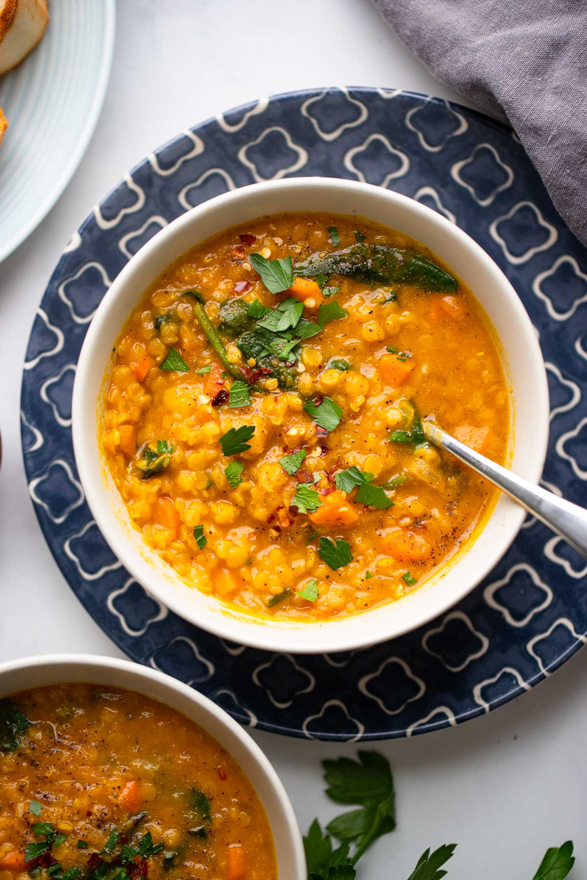 Close up red lentil pumpkin soup in bowl on blue plate.