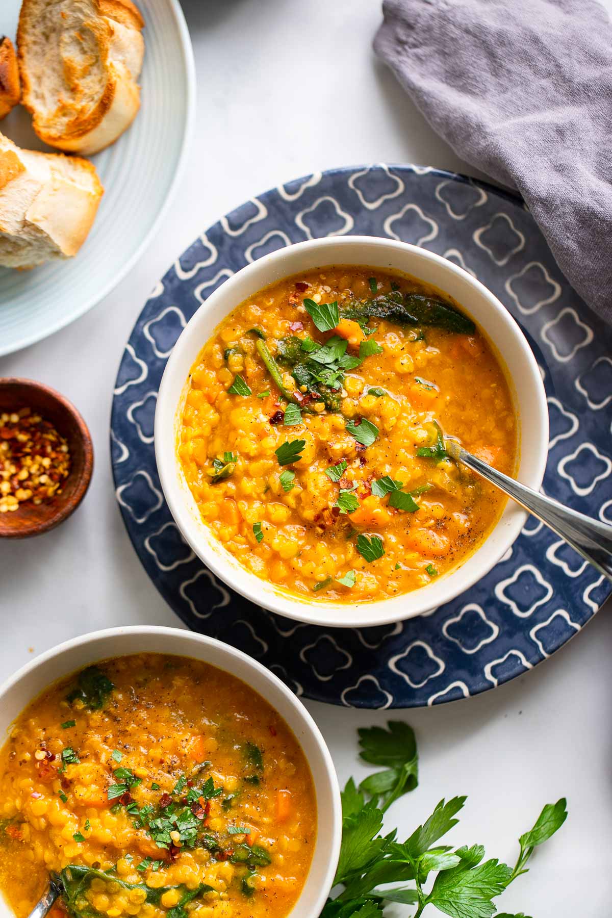 red lentil pumpkin soup garnished with parsley in bowls with bread. 