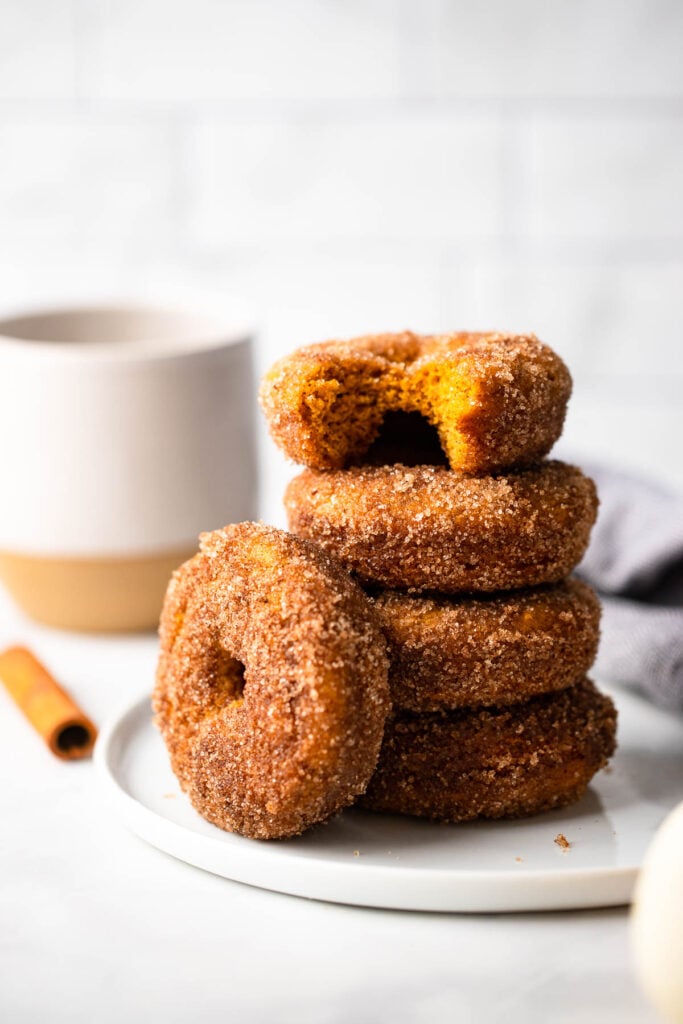 baked pumpkin donuts stacked on plate. 