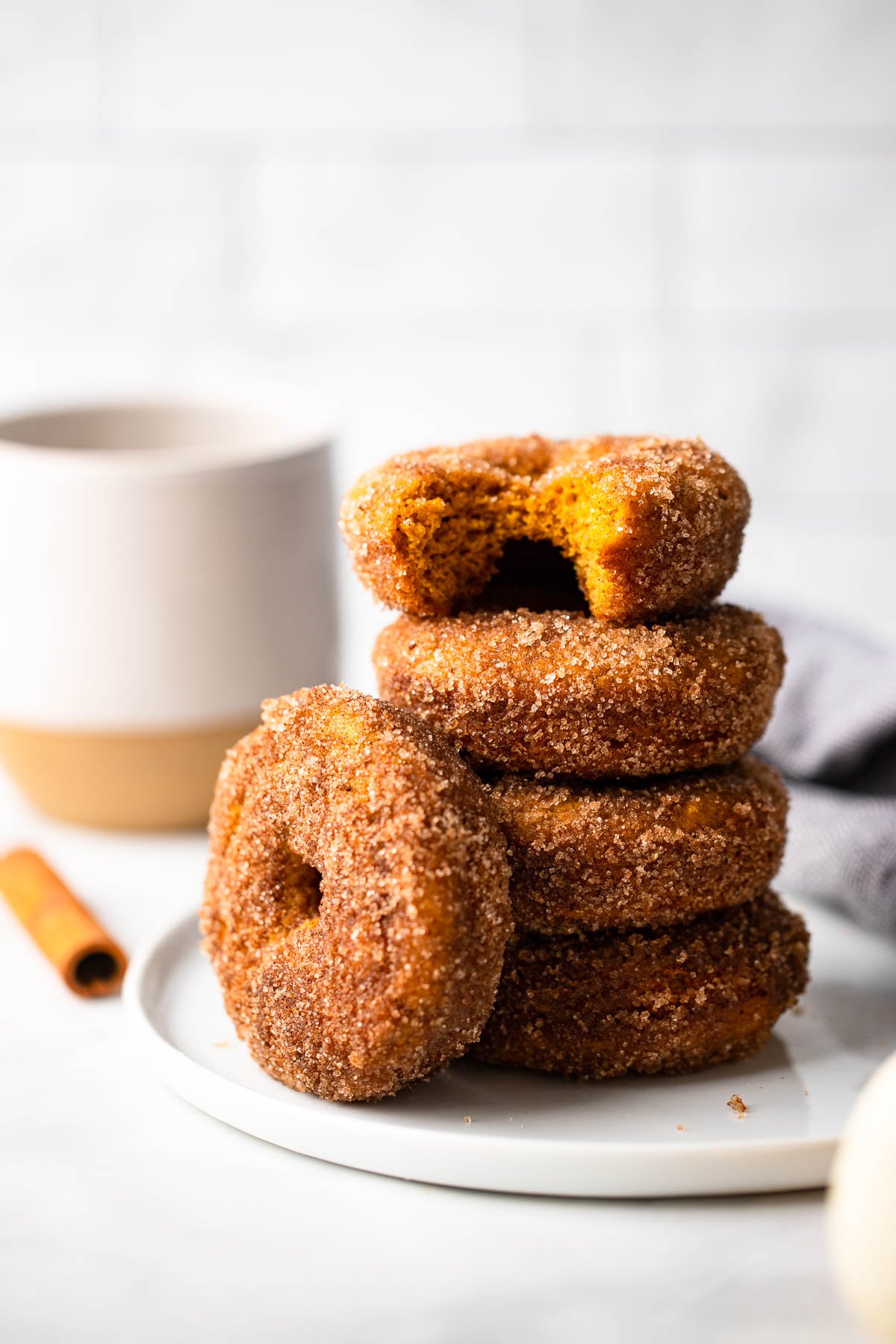 pumpkin baked donuts stacked on a white plate. 