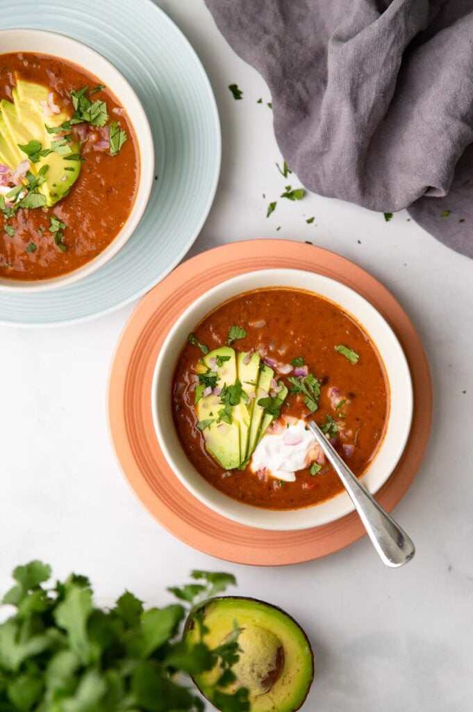 vegan black bean soup garnished with sour cream, avocado and cilantro.