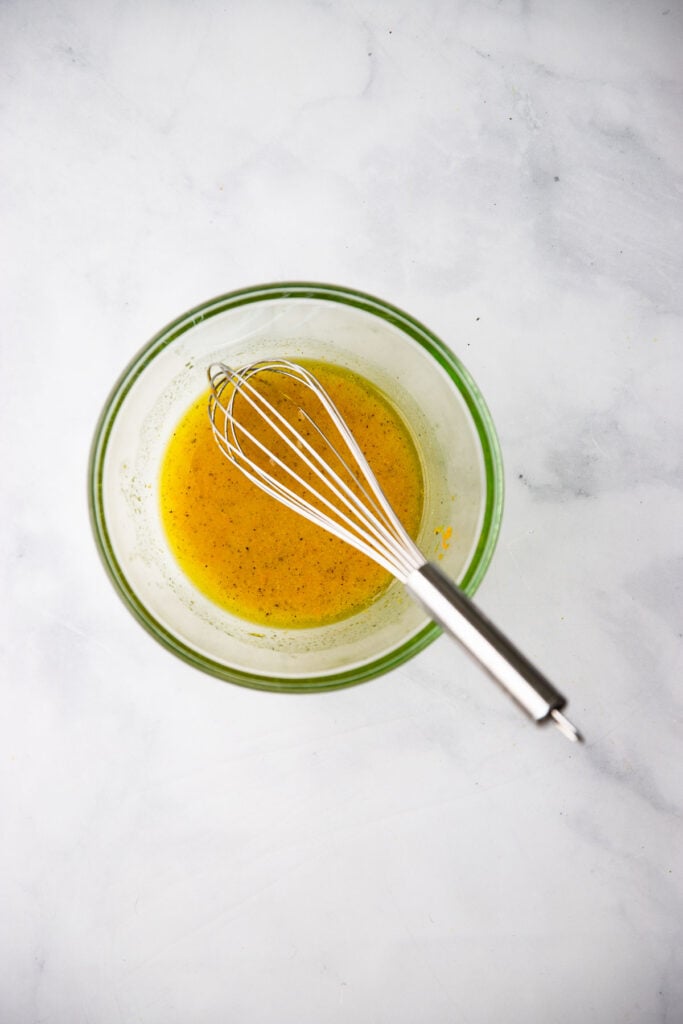 salad dressing in bowl with whisk.