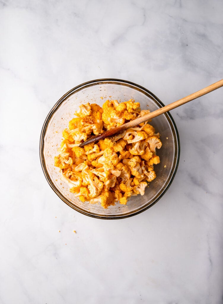 cauliflower in mixing bowl tossed with spices. 