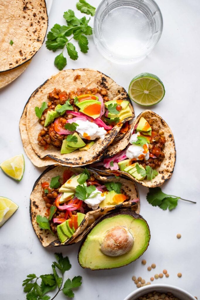 assembled lentil tacos with avocado, sour cream, and cilantro.