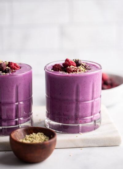 berry protein smoothie in glass garnished with berries.