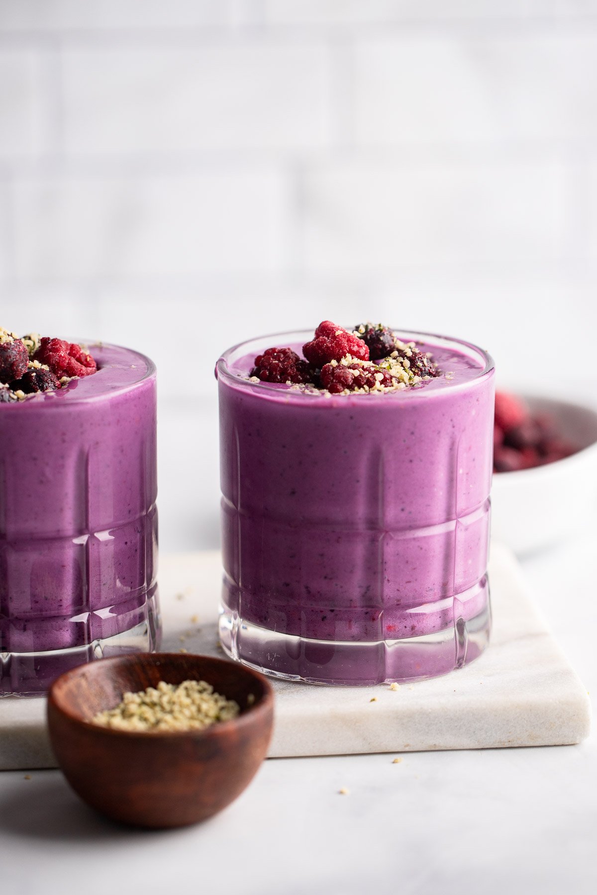 berry protein smoothie in glass garnished with berries and hemp hearts.