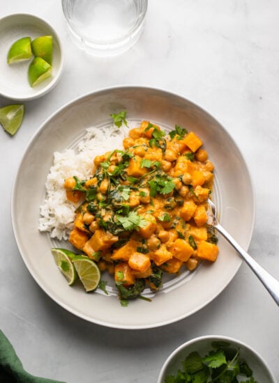 chickpea and butternut squash curry dished up on plate over rice and garnished with fresh cilantro.