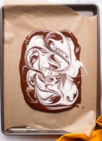 white chocolate swirls in melted dark chocolate on baking sheet.
