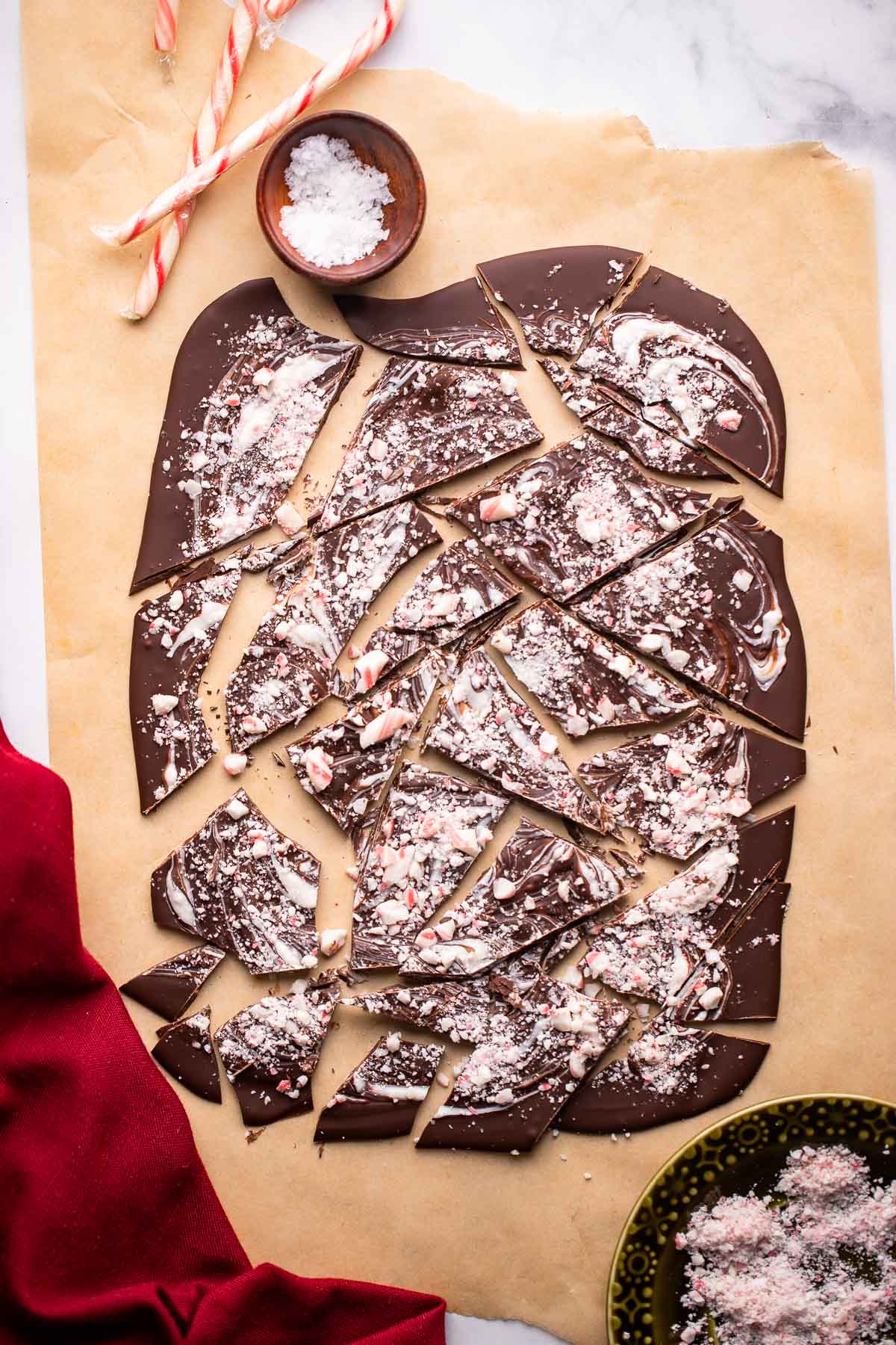 peppermint chocolate bark broken into pieces on a piece of parchment.