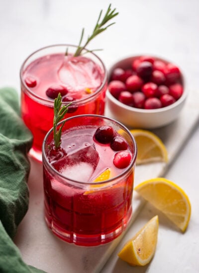 cranberry cocktail glasses garnished with fresh cranberries and rosemary sprigs.