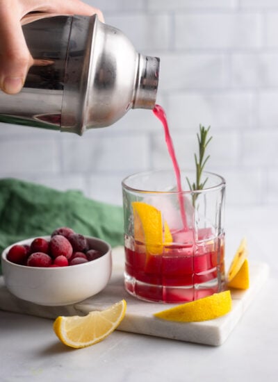 hand pouring cocktail from shaker into prepared glass. 