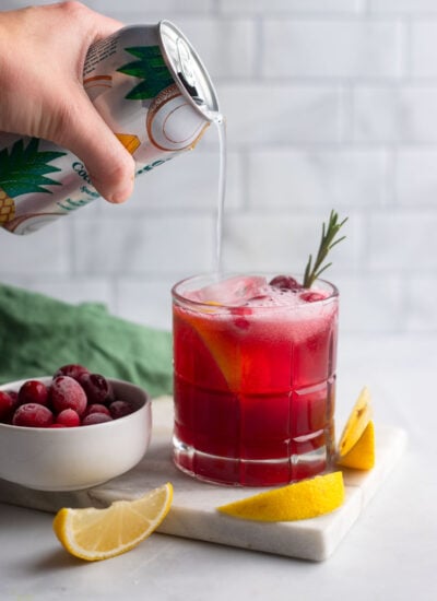 hand pouring sparkling water into cocktail glass. 