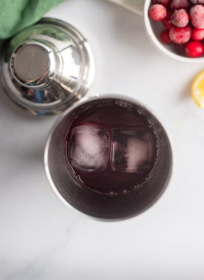 cranberry cocktail ingredients in metal cocktail shaker. 