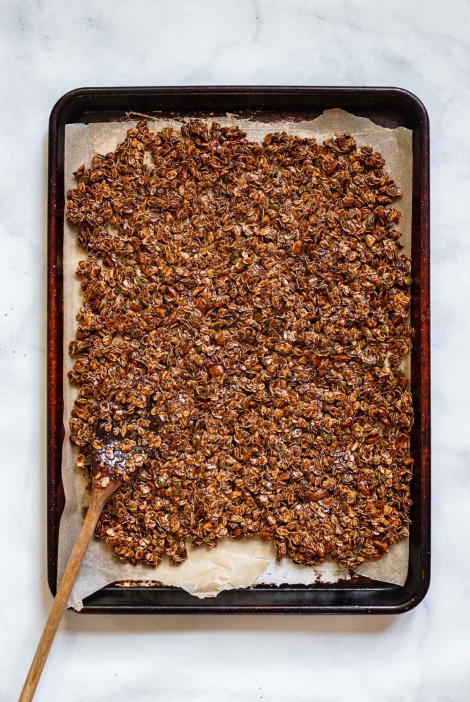 granola spread into an even layer on a parchment lined pan.