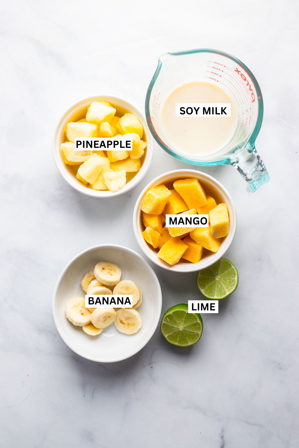 mango pineapple smoothie ingredients in small bowls with labels.