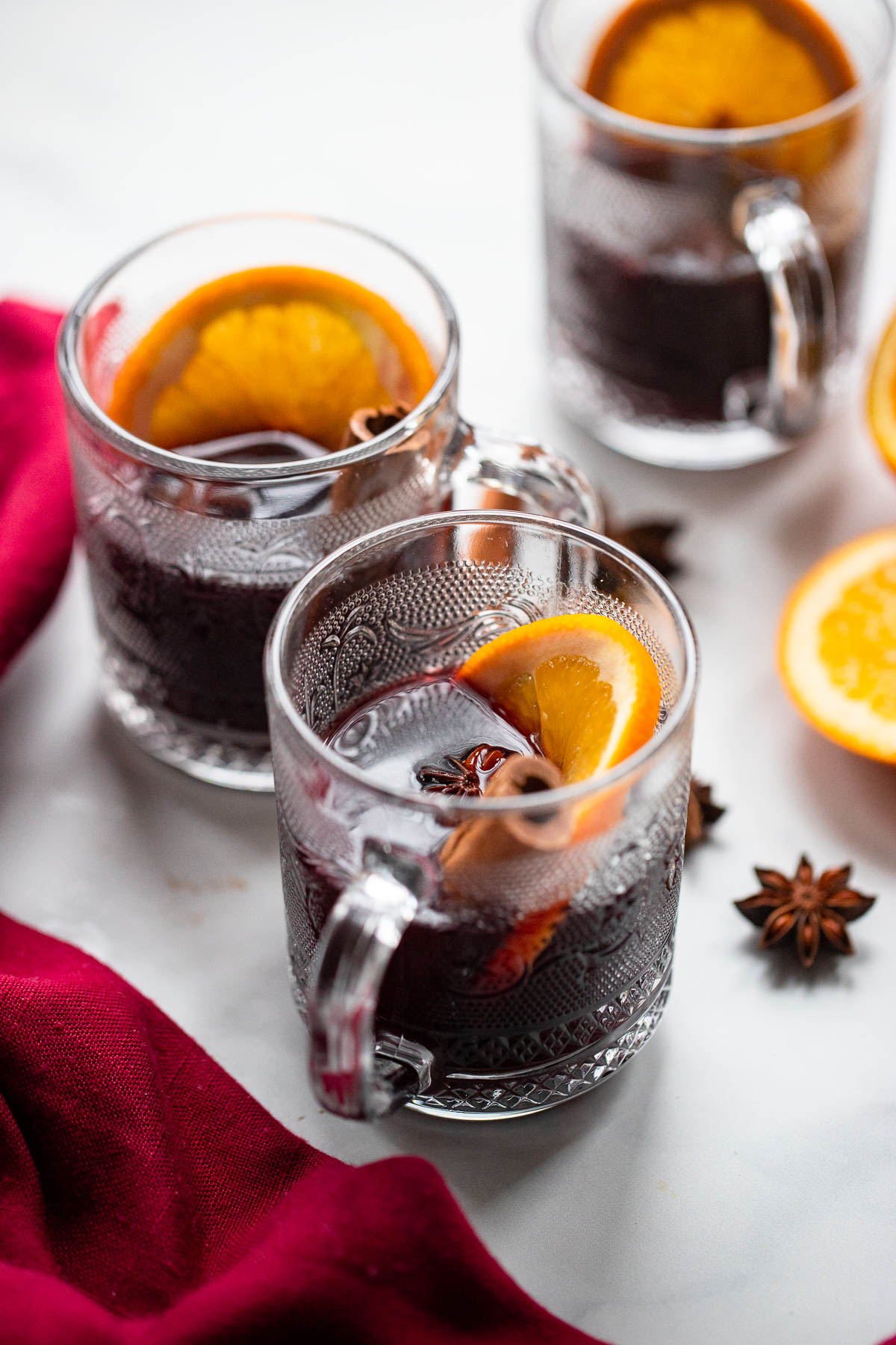 mulled wine in glass mugs with orange slice and cinnamon stick.