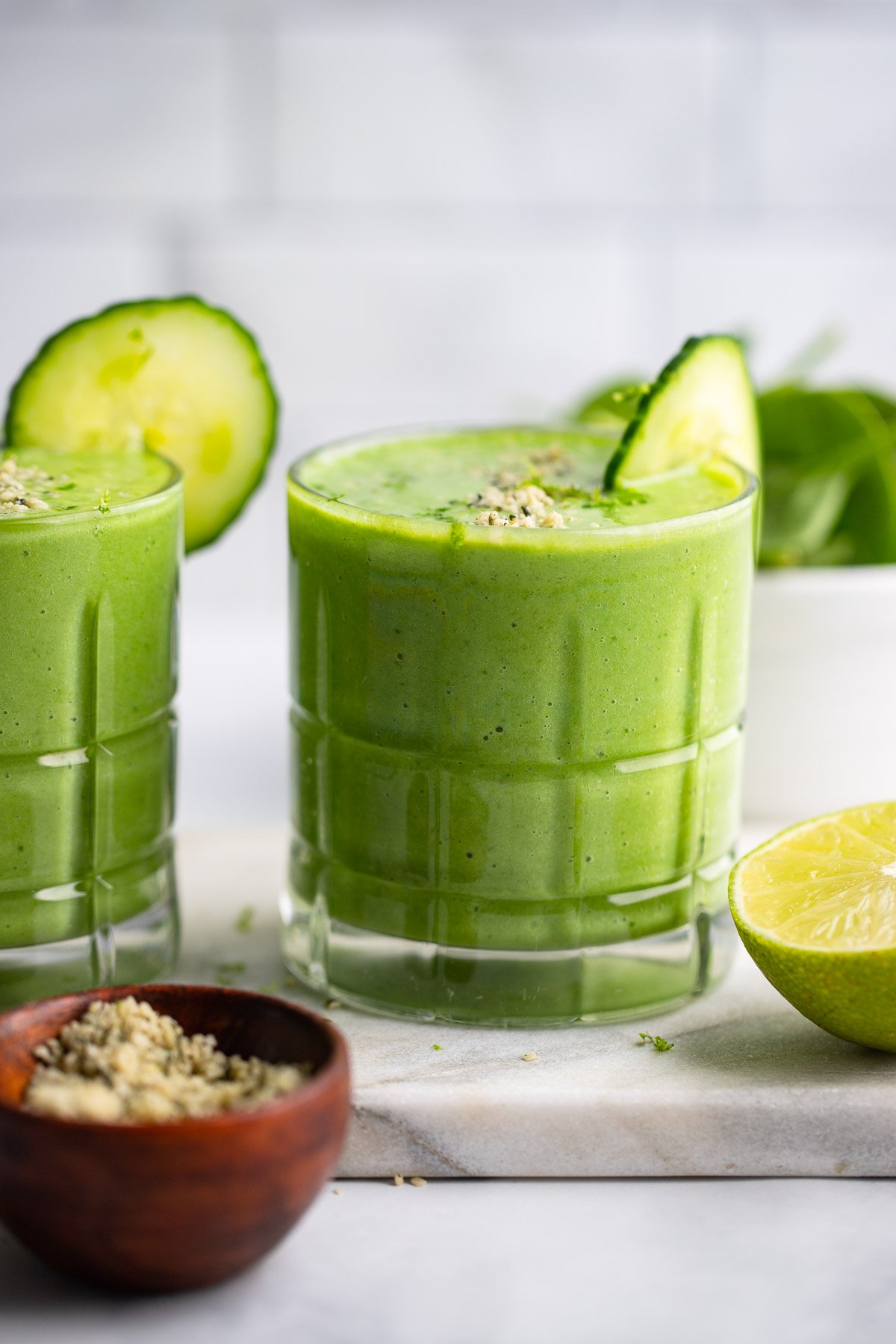 pineapple cucumber smoothie in glass with slice of cucumber.