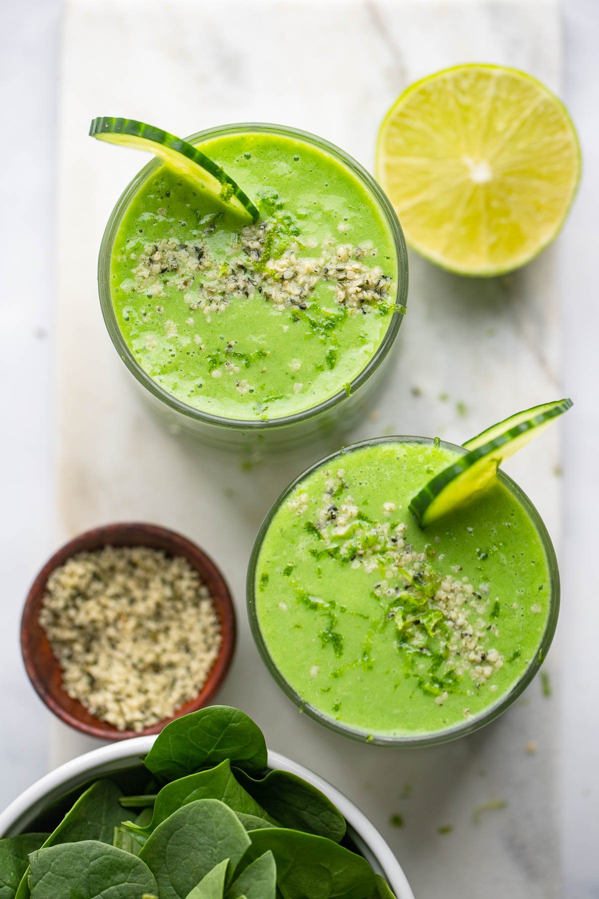 pineapple cucumber smoothie garnished with lime zest, hemp hearts and cucumber slice.