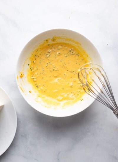 mayonnaise, turmeric, relish, mustard and seasonings whisked together in a bowl.