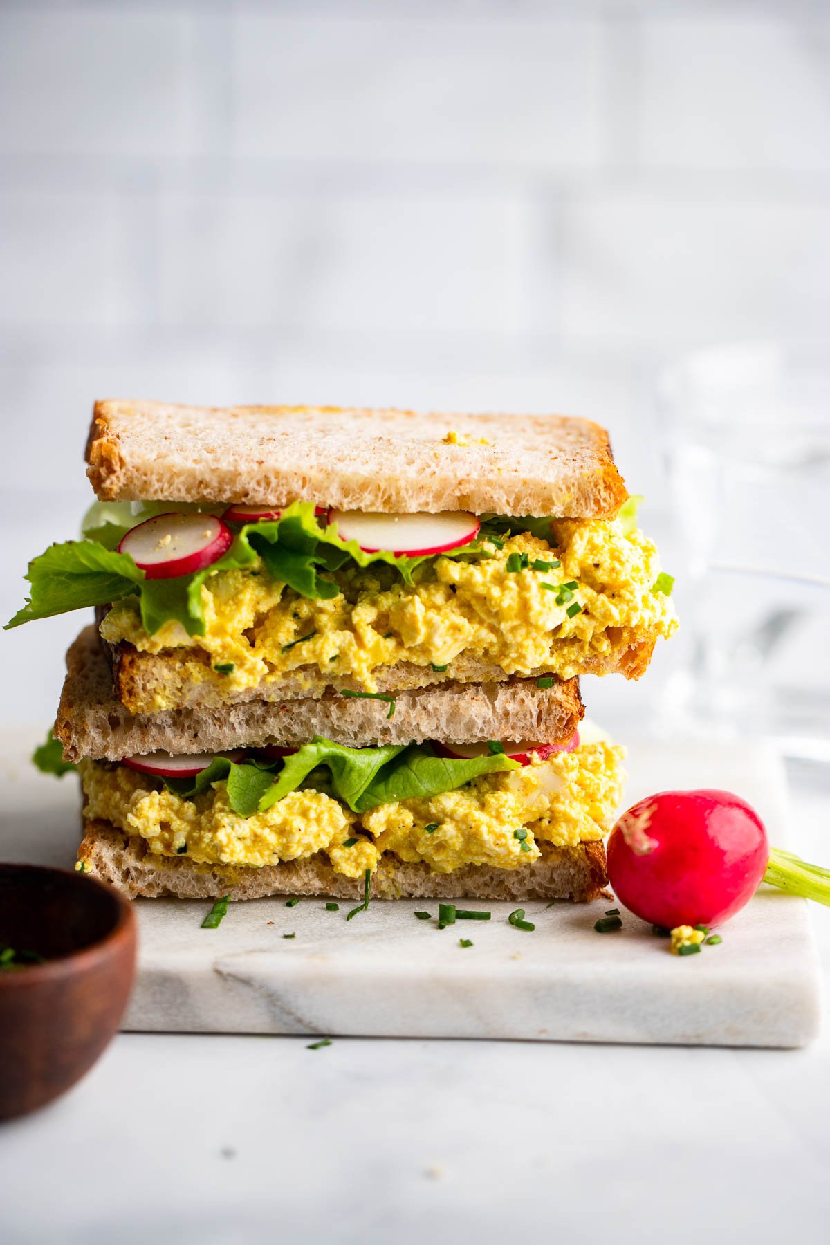 tofu egg salad sandwich halves stacked on top of each other.