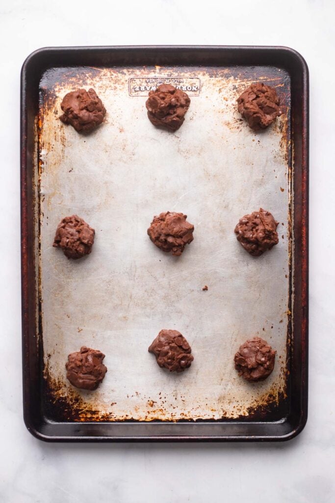 chocolate cookie dough scooped onto baking sheet.
