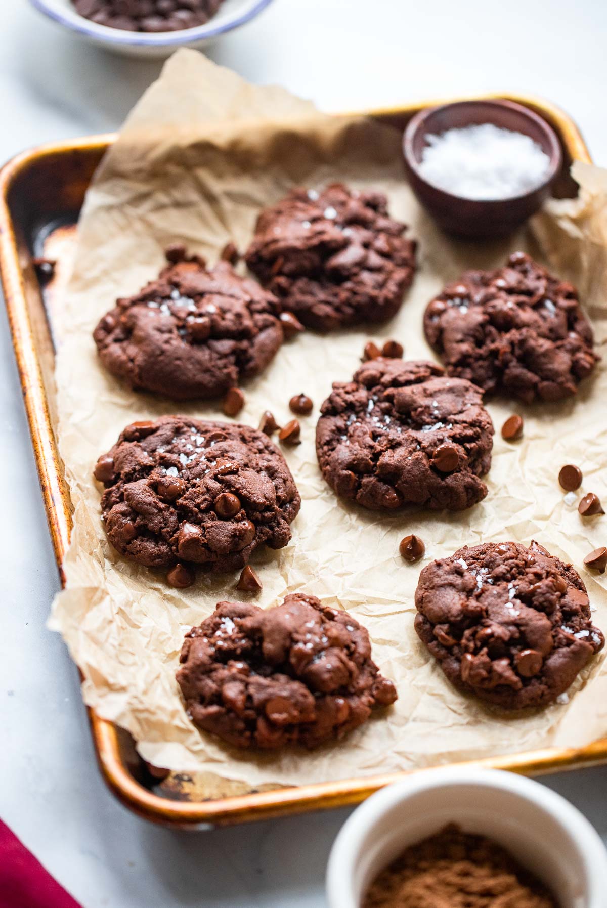 vegan double chocolate cookies on baking sheet with flaky salt on top.