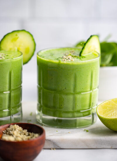 pineapple cucumber smoothie in glass with slice of cucumber.