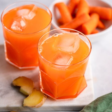 carrot ginger juice in glass with ice.