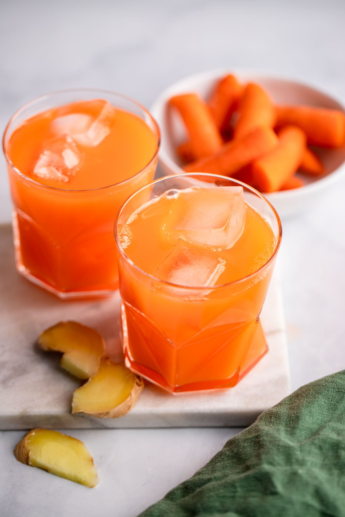 carrot and ginger juice in a glass with ice cubes.