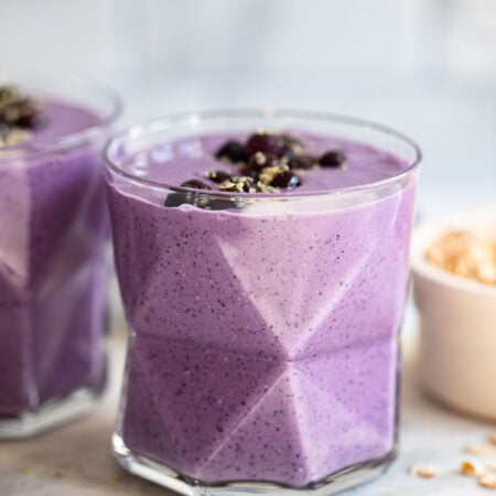 blueberry oat smoothie in glass garnished with blueberries.