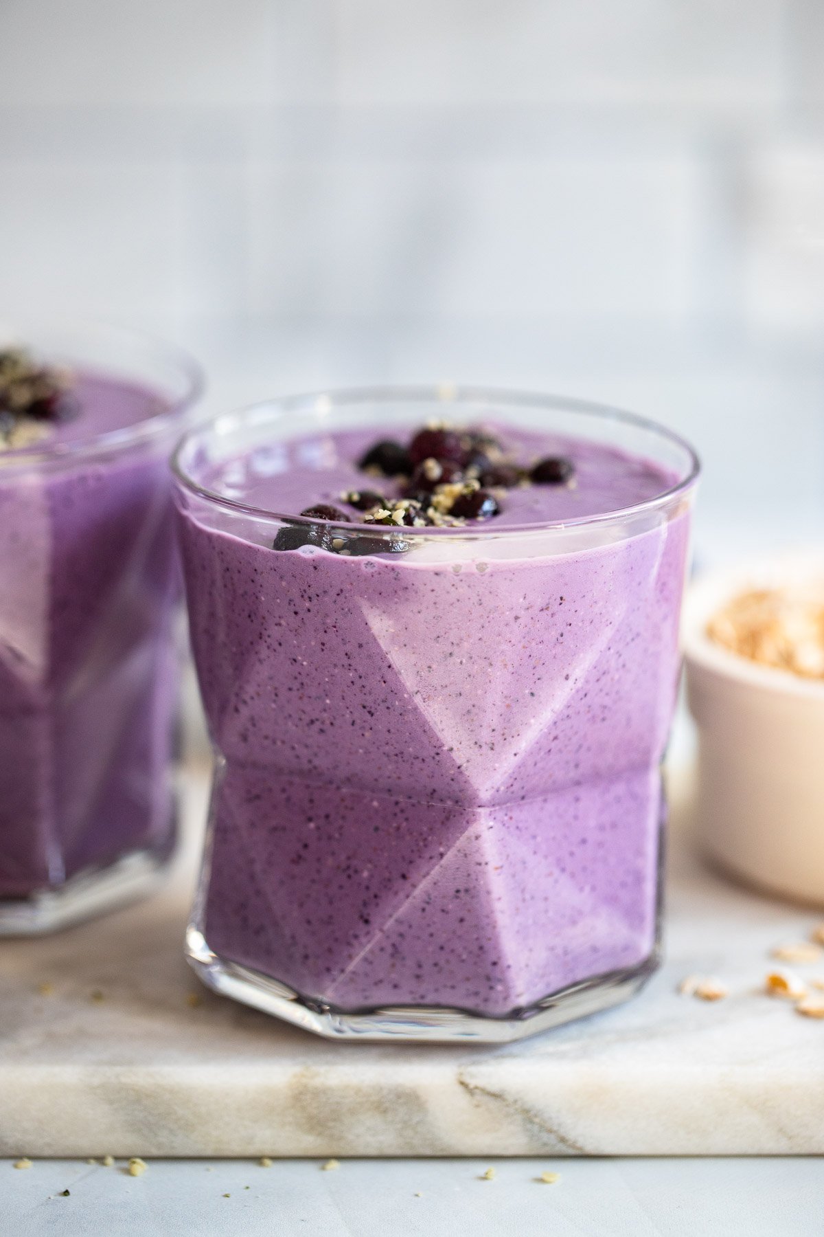 blueberry oat smoothie in glass garnished with blueberries.