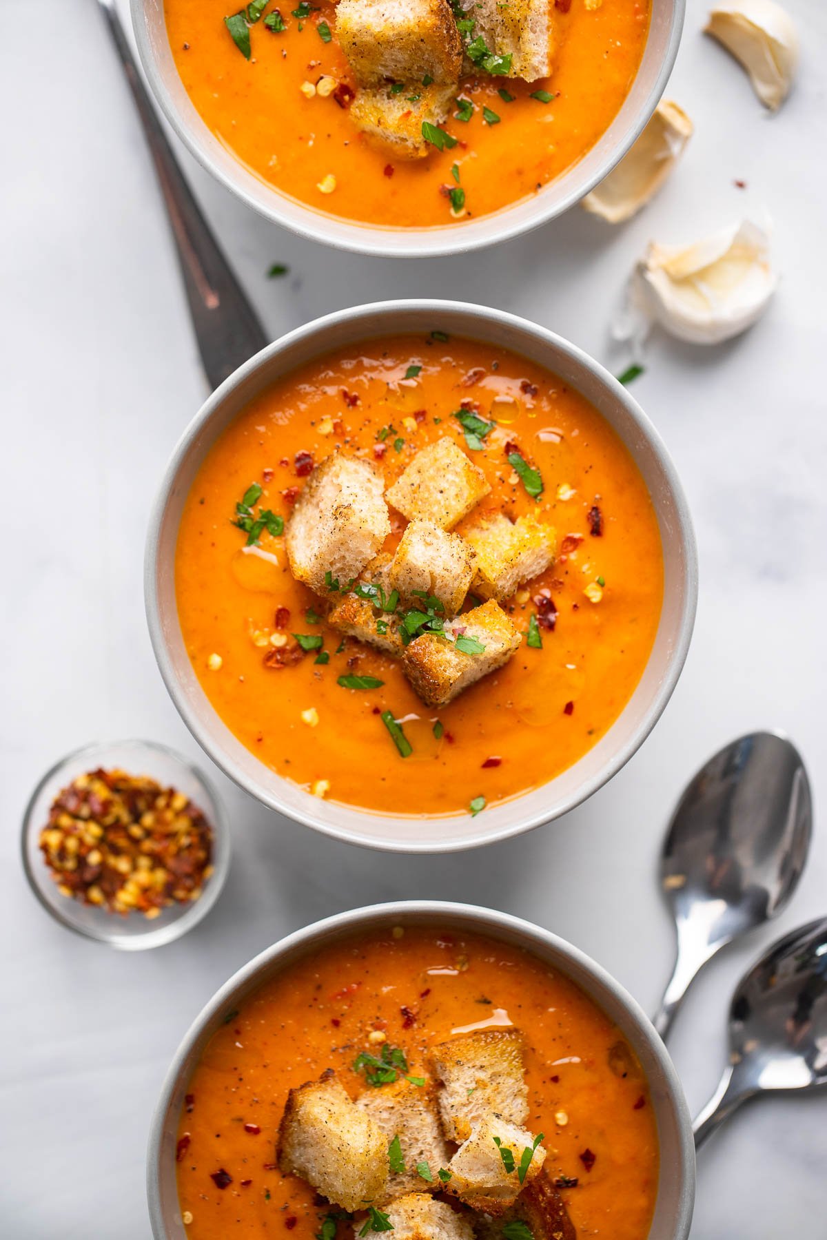 butternut squash and red pepper soup in bowl garnished with croutons and fresh parsley.