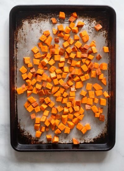 chopped sweet potatoes added to a baking sheet. 