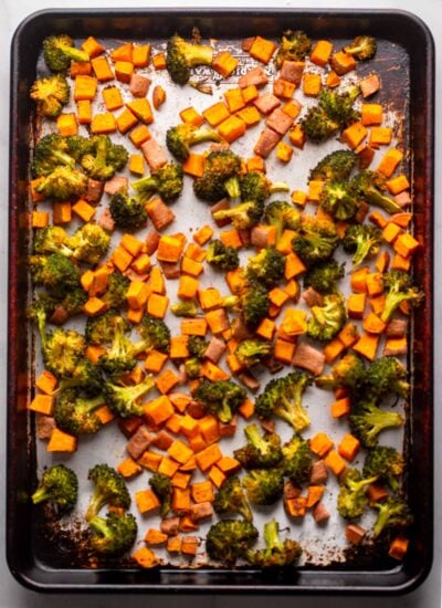 roasted broccoli and sweet potatoes on a baking sheet. 