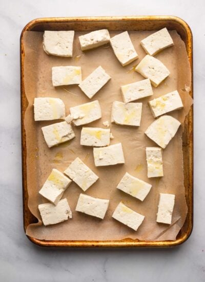 parchment lined baking sheet with cubed tofu lightly covered in cooking oil.