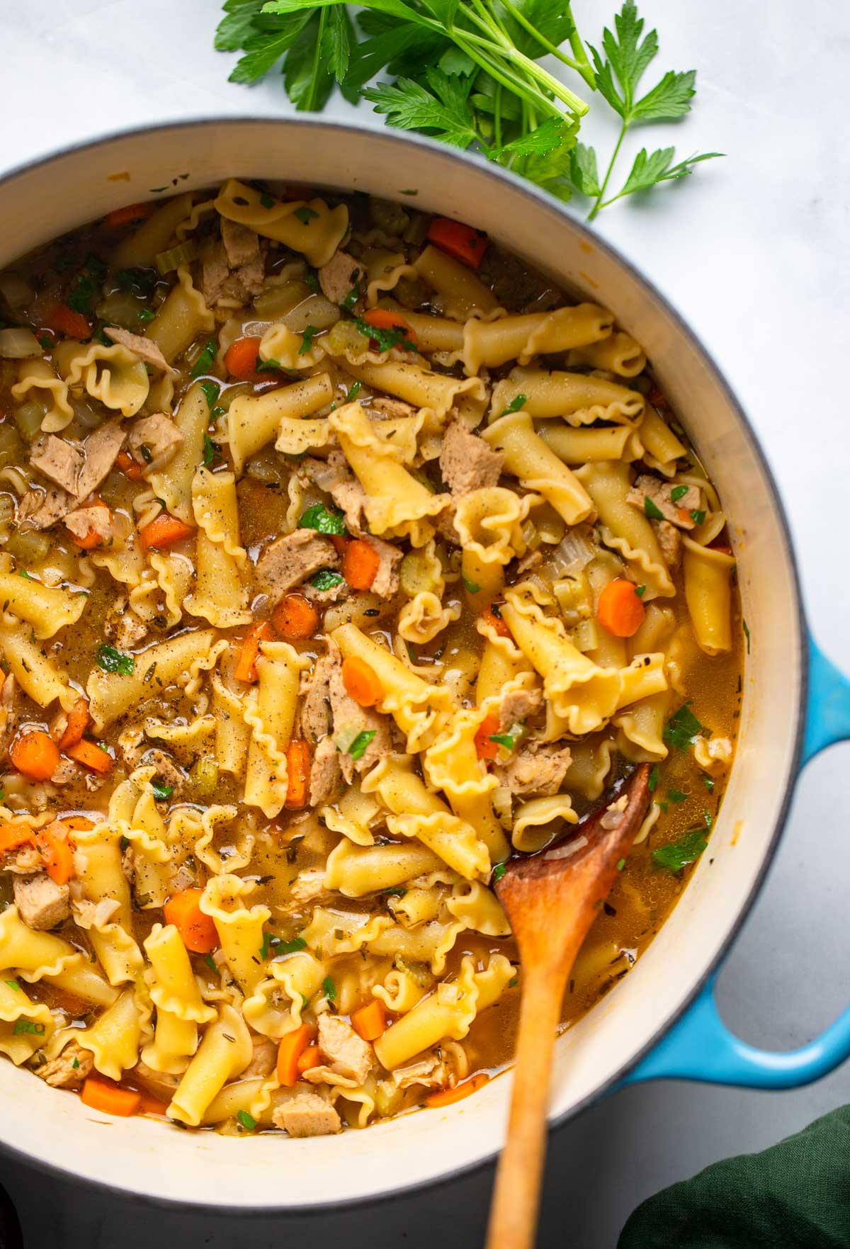 vegan chicken noodle soup in a dutch oven with a wooden spoon.