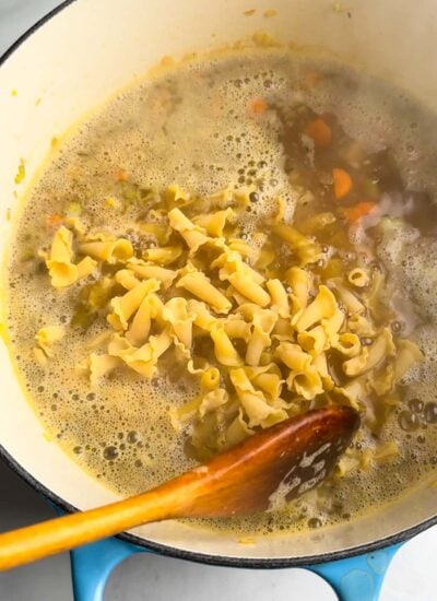 dry noodles added to the pot of vegan chicken noodle soup.