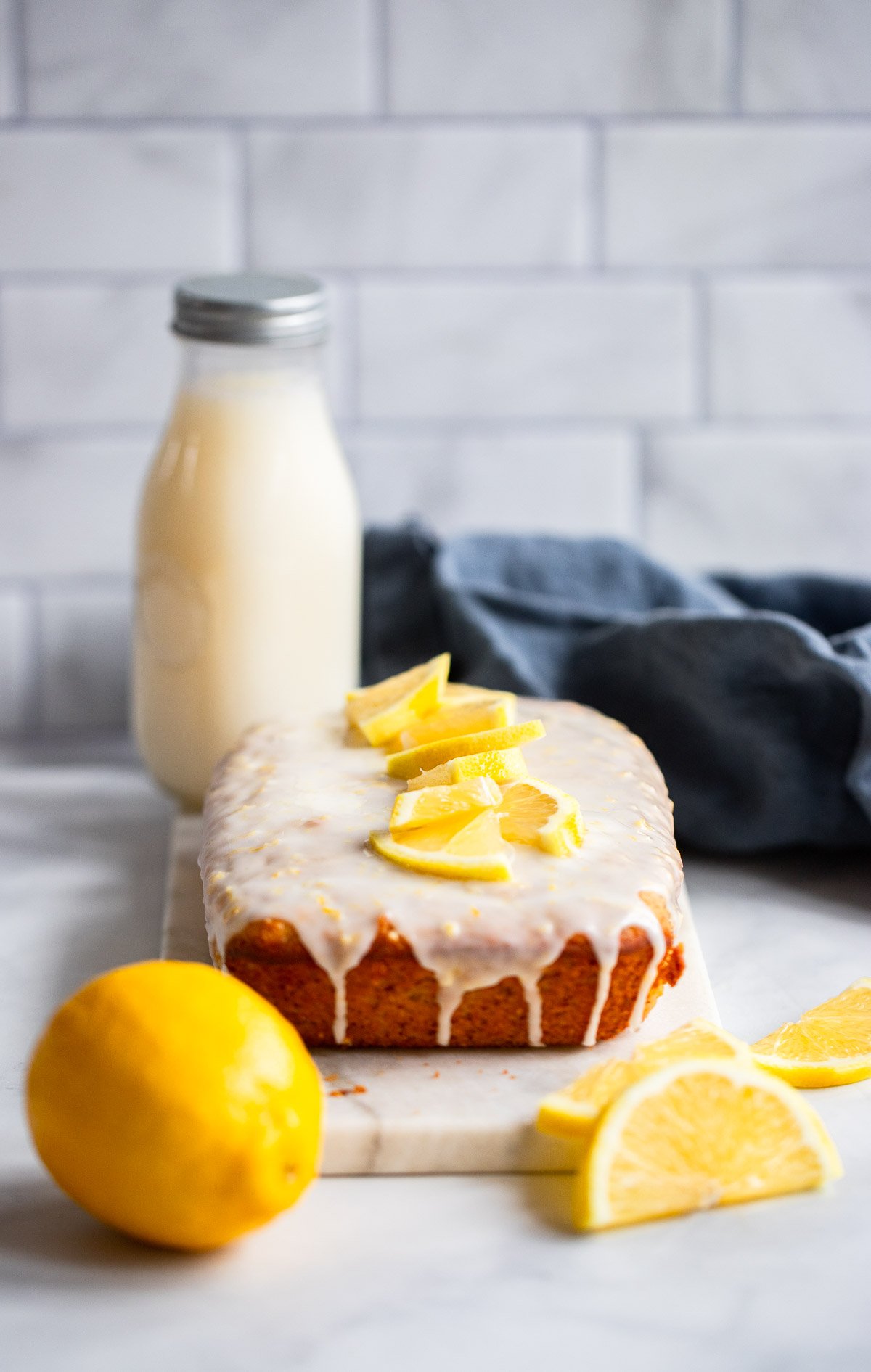 vegan lemon loaf on marble slab with fresh lemon slices.