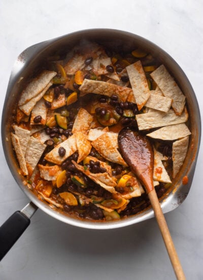 skillet with enchilada sauce, black beans, and chopped tortillas added.