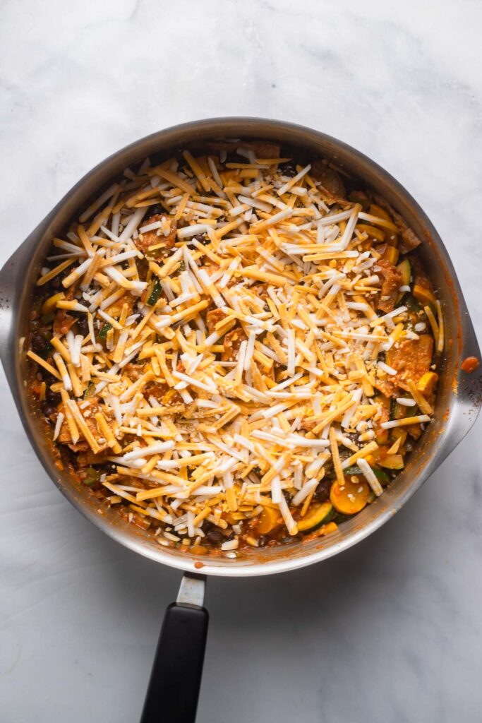 enchilada skillet with shredded cheese on top before melting.
