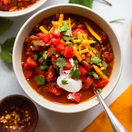 vegetarian chipotle chili in bowl garnished with cheese, tomatoes, and sour cream.