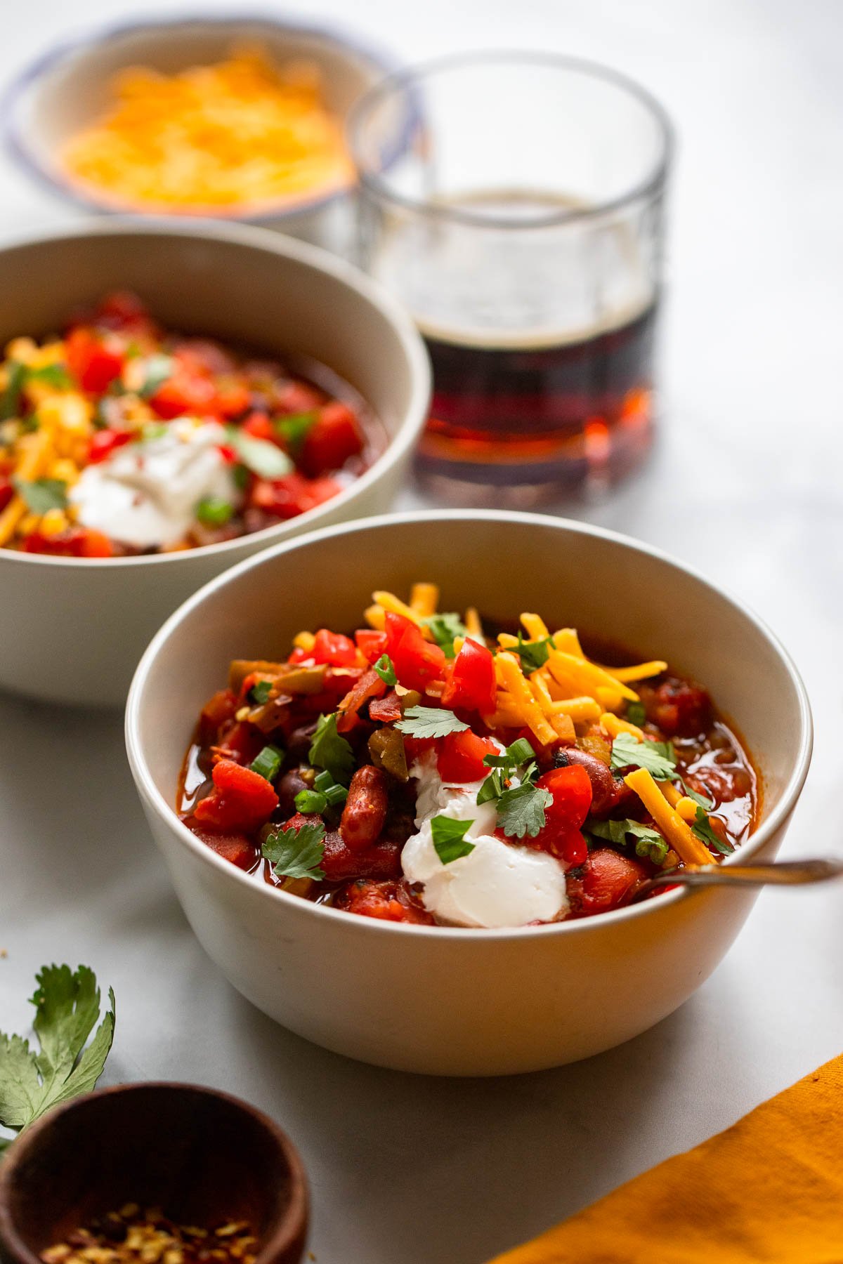 chipotle chili in bowl garnished with shredded cheese, sour cream, tomatoes, and cilantro.