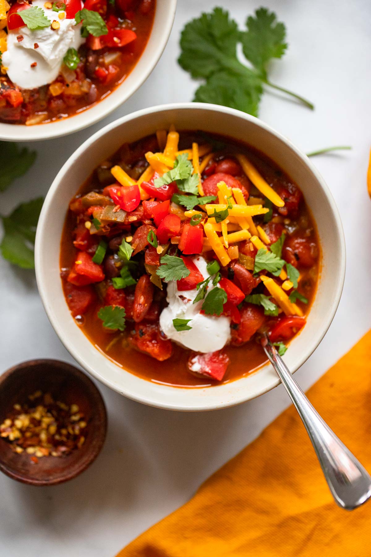 vegetarian chipotle chili in bowl garnished with cheese, tomatoes, and sour cream.