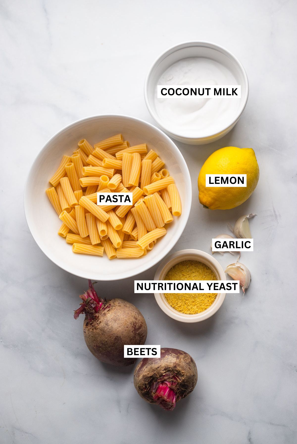 beet pasta sauce ingredients in bowls with text overlays that say: coconut milk, lemon, pasta, garlic, nutritional yeast, and beets. 
