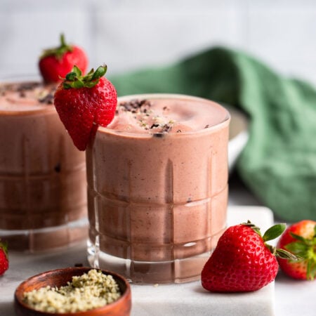 chocolate strawberry banana smoothie in glass with fresh strawberry to garnish.