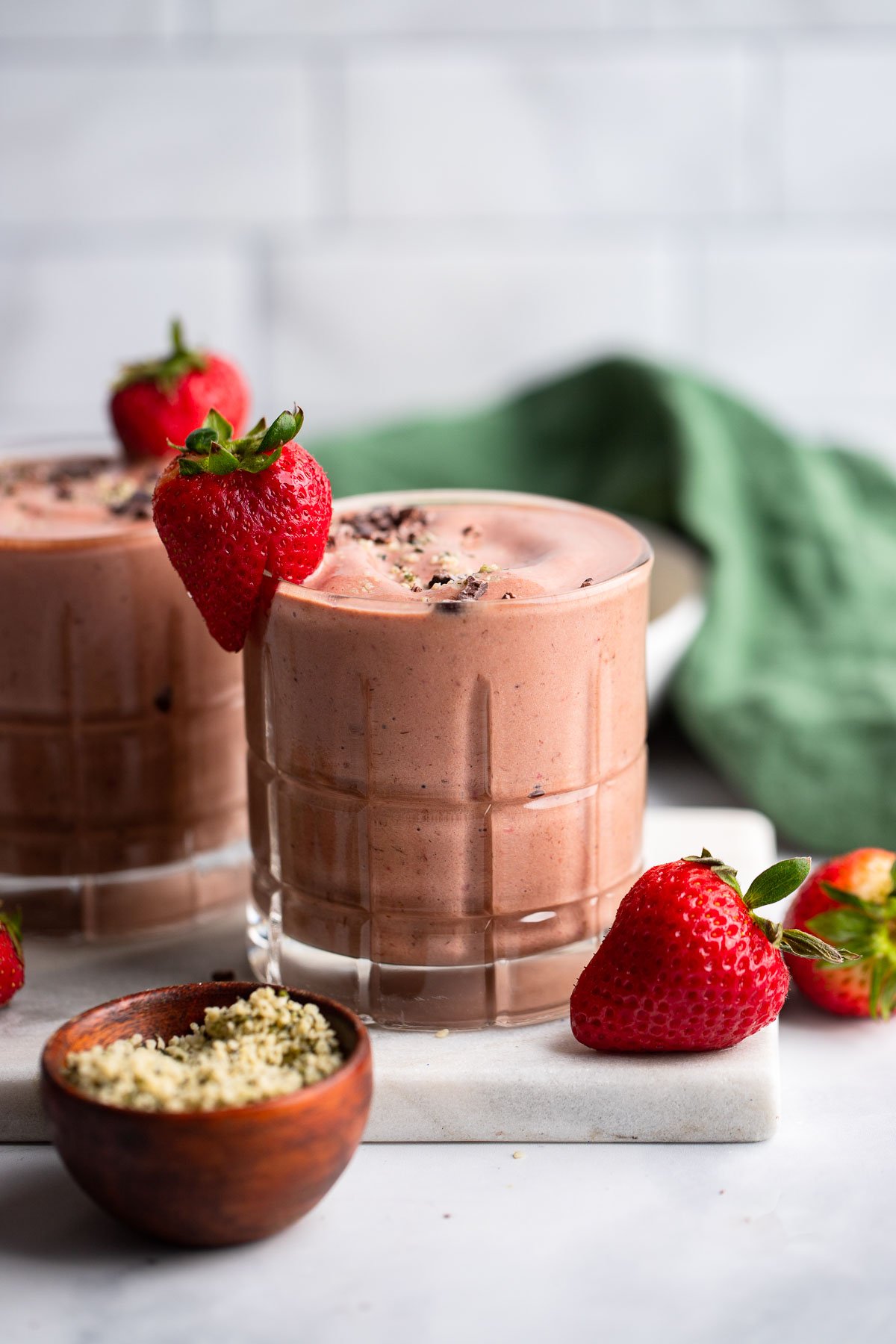 chocolate strawberry banana smoothie in a glass garnished with hemp hearts and a fresh strawberry.