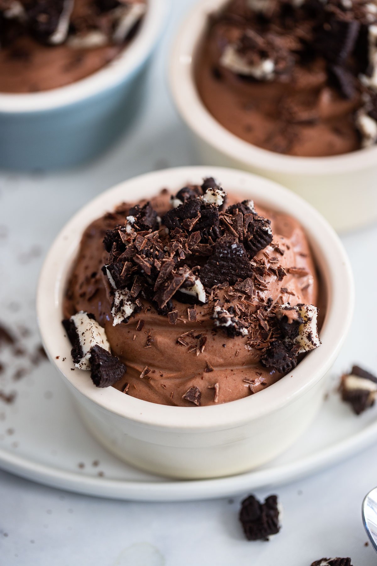 chocolate tofu mousse in small white ramekin topped with crumbled cookies. 