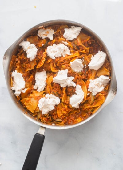 spoonfuls of vegan ricotta added to the top of the cooked lasagna skillet. 